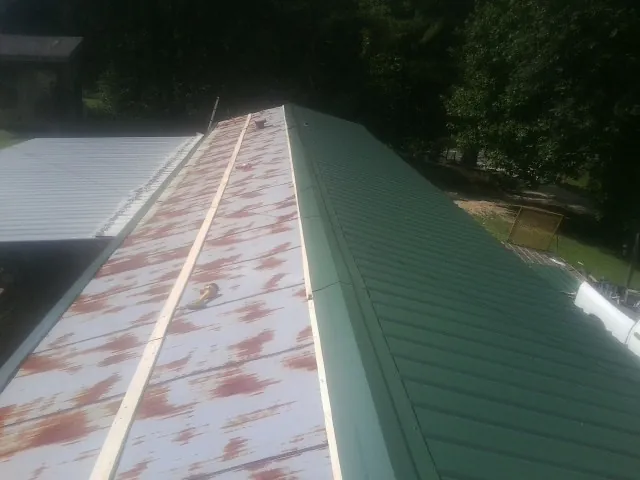 Old rusted panels beside newly installed green metal roofing — Wind Damage Roof Repair by Roofing Brothers in Lewisberry