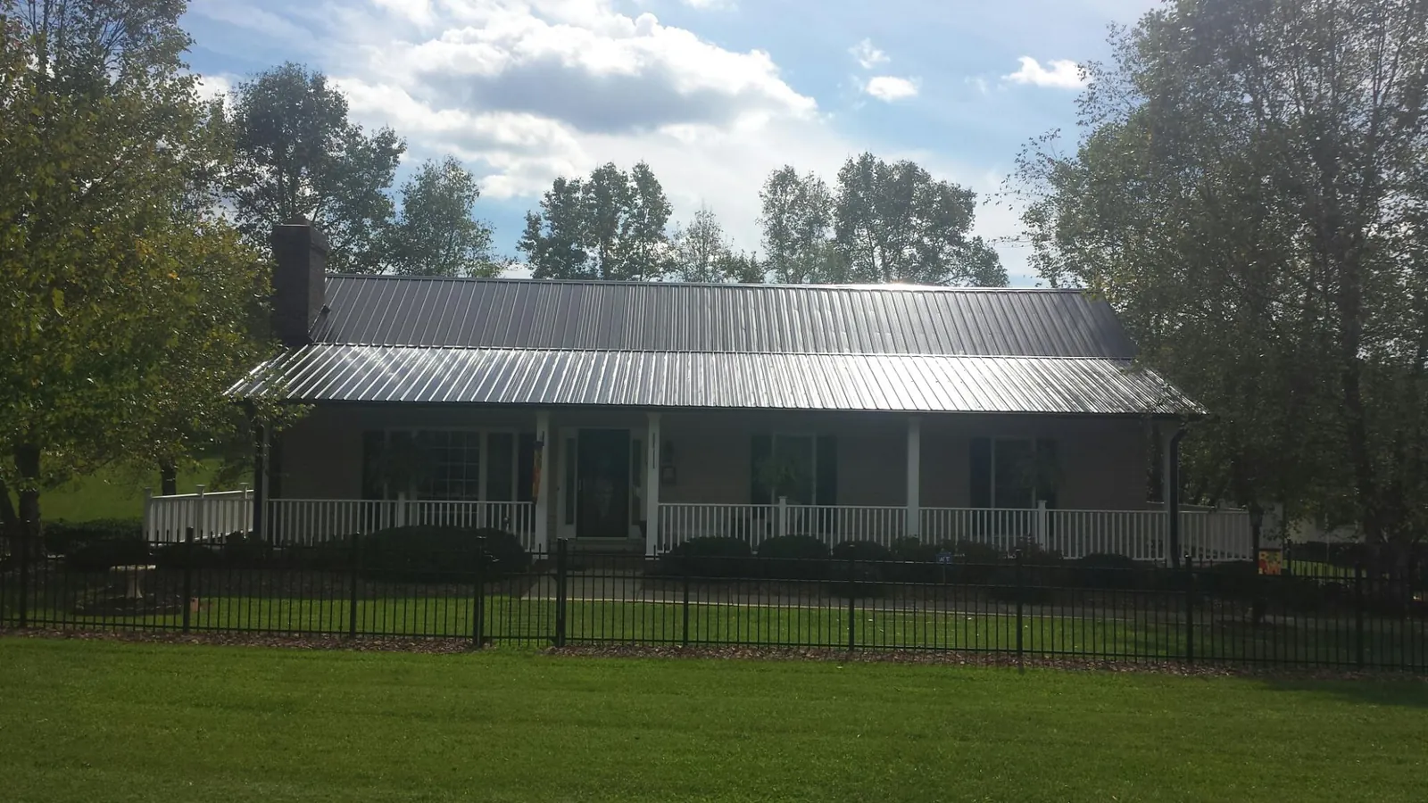 Gray metal roof on a brick ranch with a full width front porch — Gutter Guard Installation work by our crew in Lewisberry
