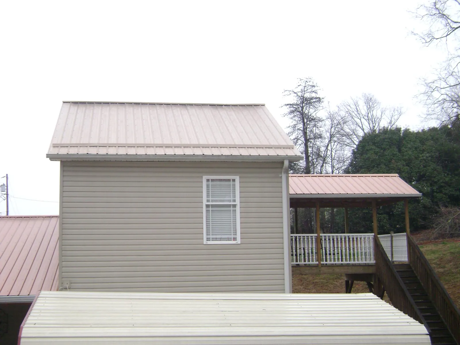 Tan metal roofs on a two story addition and attached porch, from a Roof Replacement job in Lewisberry